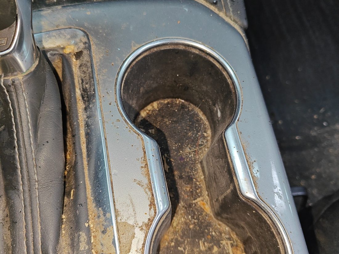 Cup holder filled with built up coffee residue and debris before cleaning