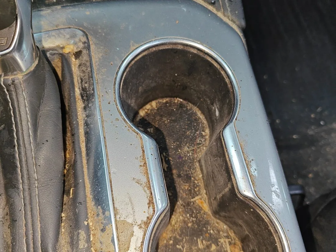 Cup holder filled with built up coffee residue and debris before cleaning
